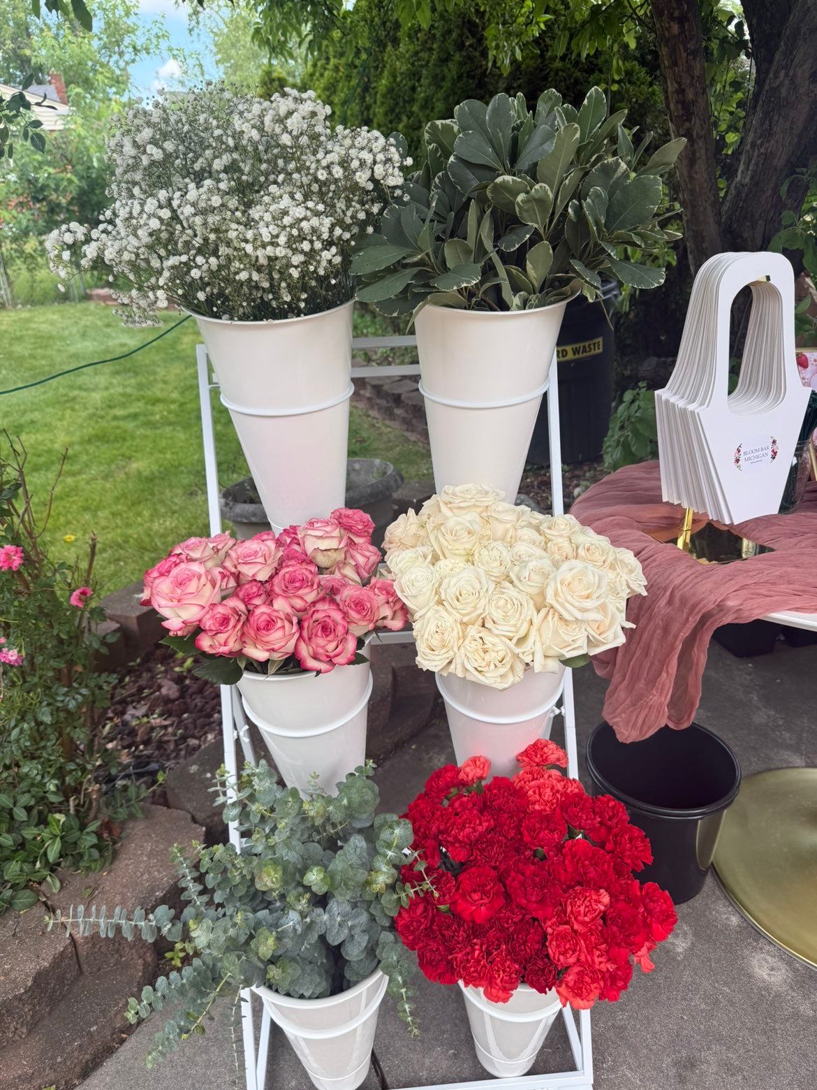 White Bloom Bar stand with baby's breath, bicolor roses and red carnations at a backyard party