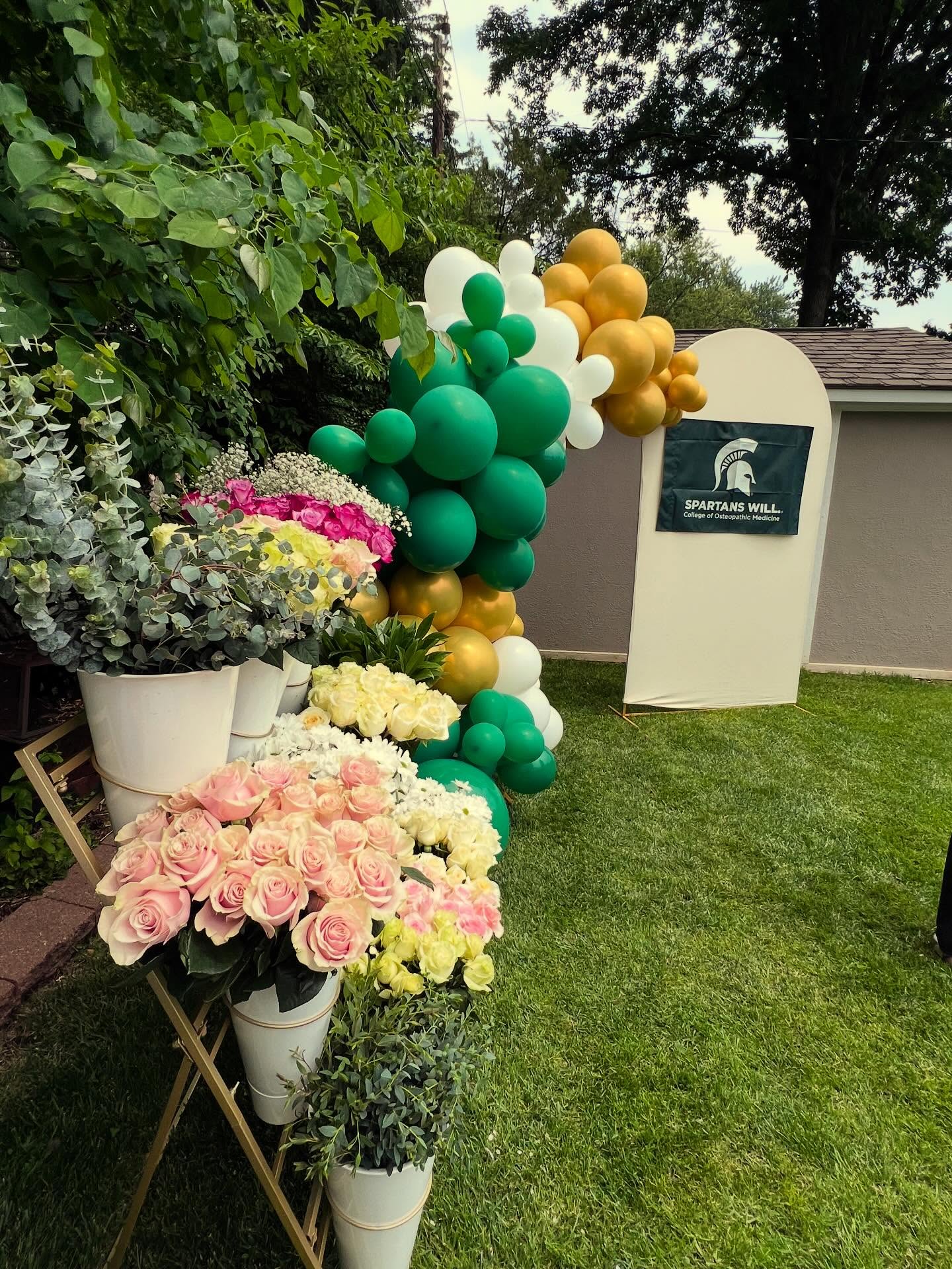 Bloom Bar flowers with green and gold balloon garland at a graduation party