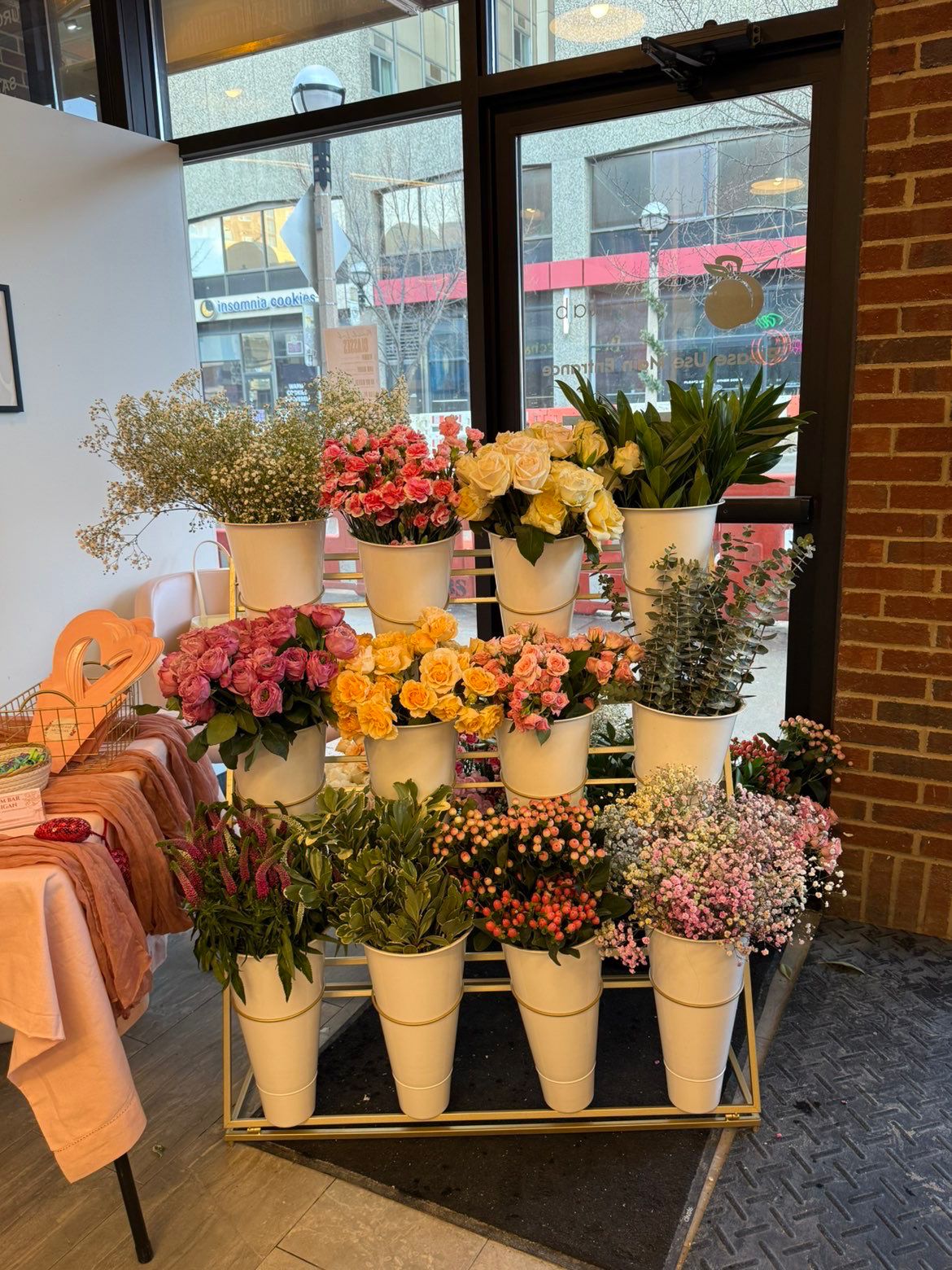 Bloom Bar stand with peach, yellow and pink blooms in a storefront window